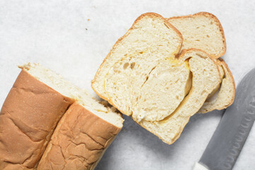 Overhead view of slicing homemade loaf of bread, top view of white bread being sliced