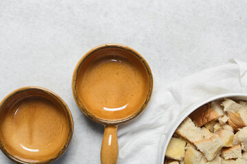 Top view of brown ceramic ramekins on a white marble countertop, terracotta ramekins with handles on a white background