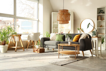 Interior of stylish living room with grey sofa, coffee table and mirror