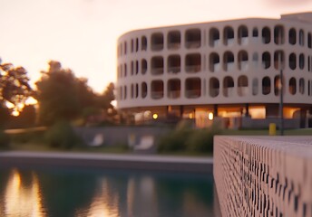 Obraz premium Warm Sunset Illuminating Modern Architectural Building by a Tranquil Lake