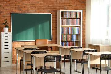 Blank blackboard on brick wall in classroom interior