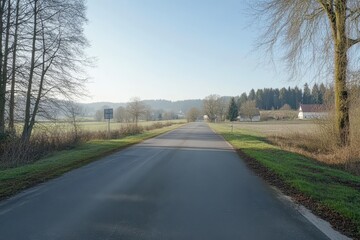 Fototapeta premium Empty road through rural landscape. A paved road stretches through a serene countryside. 