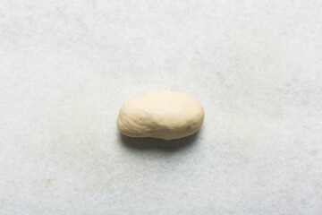 Overhead view of homemade pretzels dough being shaped on a white countertop, top view of soft pretzel dough on a white background