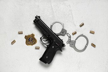 Police officer's shield, gun, bullets and handcuffs on light background