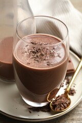 Tasty chocolate milk with shavings on wooden table, closeup