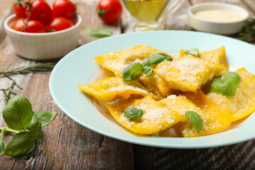 Delicious ravioli with cheese and basil served on wooden table, closeup