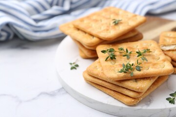 Tasty salty crackers with thyme on white marble table, closeup. Space for text
