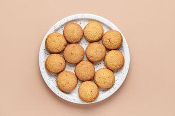 Plate with sweet cookies on brown background