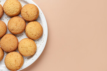 Plate with sweet cookies on brown background