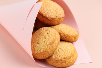 Paper cone with sweet cookies on pink background, closeup