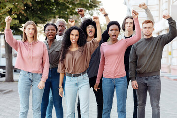 Multiethnic protestors striking against racism on the street, closeup. International group of young people making riot next to government building. Racism, discrimination concept