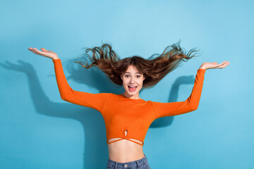 Excited young woman in vibrant orange top showcasing her energy and charm against a picturesque...