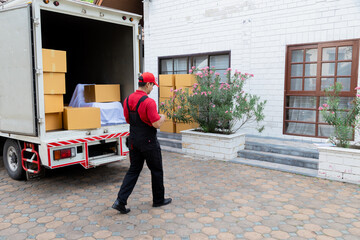 Fototapeta premium Professional house moving employees worker in uniform work uploading furniture to cargo truck to new house, teamwork Indian man and Caucasian delivery moving house services logistic business industry
