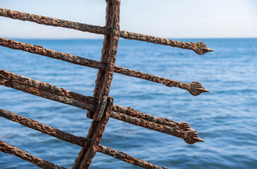 Rusty iron railing made in the shape of an arrow. Sharp-end iron bars. sea background.
