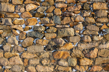 Old stone wall covered with snow. Weathered rough masonry surface. Texture for background and design.