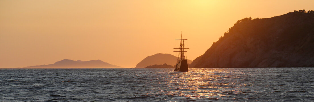 A tall ship sailing on the Adriatic sea at sunset.