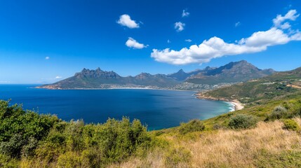 Obraz premium Coastal view of a bay with mountains, beach, and clear blue skies