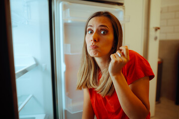 Woman Lacking Money and Showing her Empty fridge. Unhappy person struggling during economic...