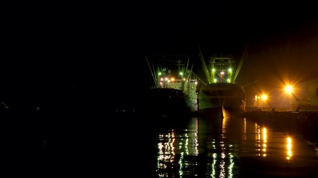 怪しい雰囲気がする無人の夜の港と停泊中の貨物船