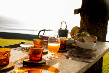 breakfast table on a sunny day in a garden facing the sea outside with close-up of cold coffee cups...