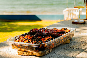 plate of black spaghetti with prawns and octopus close-up seafood on a sunny day facing the sea outside in a garden with grass