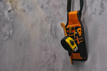 Tool belt with essential construction tools such as a measuring tape, utility cutter, pencil, and...