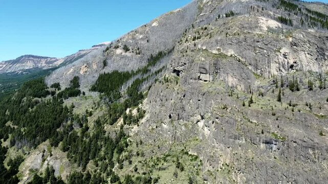 Vuelo de dron acercandose a una imponente cordillera patag&oacute;nica con una cueva y escarpadas rocas.