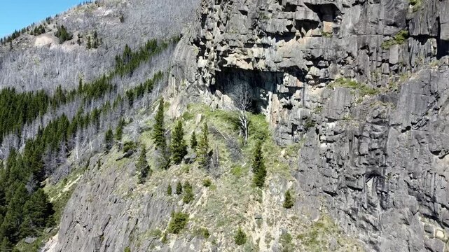 Vuelo de dron acercandose a una imponente cordillera patag&oacute;nica con una cueva y escarpadas rocas.