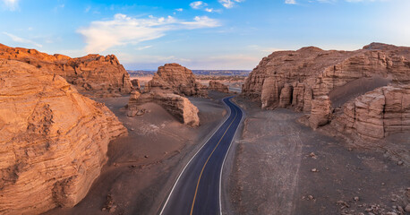 A road winding through the Yardang landform at sunset. Famous Dahaidao no man's land natural landscape in Xinjiang, China.
