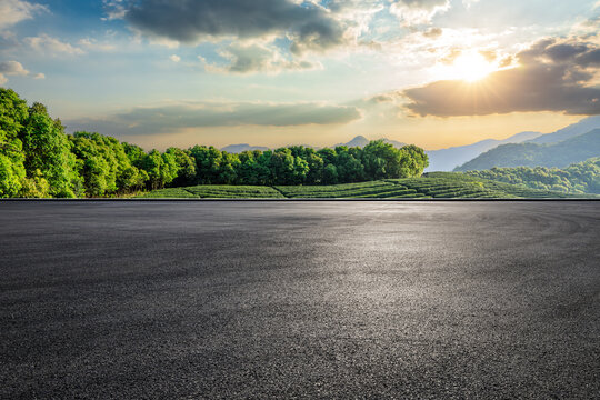 Empty asphalt road and green tea plantation with mountain natural landscape at sunset
