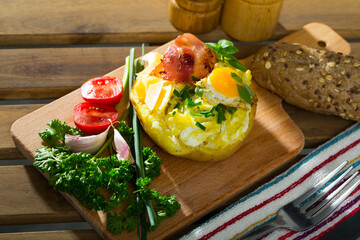 Baked potatoes served with fried egg, bacon and cheese, garnished with fresh scallions ..