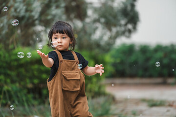 toddler girl playing soap bubble in park