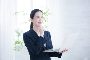 パソコンを持ちながら前向きに検討する考える見上げる女性