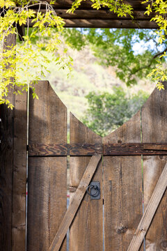Rustic wood garden gate with green trees and hills in background