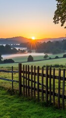 Obraz premium Serene Sunrise over Misty Green Fields with Wooden Fence