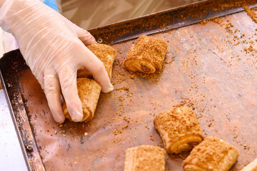 Freshly baked rolls being prepared with cinnamon sugar in a kitchen during afternoon cooking session