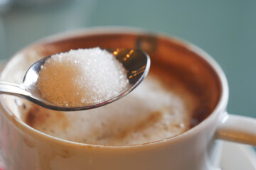 Sugar being added to a hot beverage at a cozy cafe table