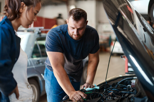 People, mechanic and car engine with teamwork, maintenance or inspection for vehicle issue. Employees, entrepreneur or coworkers with industry, auto repair shop or cooperation with solution in garage