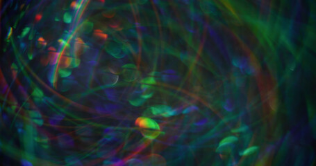 Christmas lights. Defocused firework. Multicolored blue green particles lens flare swirling on modern blurred with bokeh effect background.