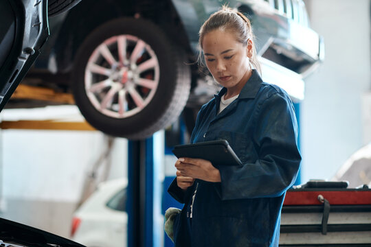 Tablet, checklist and woman in workshop with car service, maintenance or online motor insurance. Tech, engine and female mechanic in garage on digital app for inspection, repair and quality assurance - Powered by Adobe
