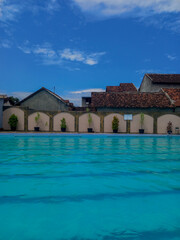 Portrait of an outdoor swimming pool surrounded by high walls with a view of the sky