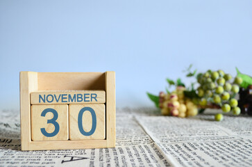 November 30, Calendar cover design with number cube with fruit on newspaper fabric and blue background.	