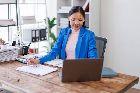 Brunette young asian businesswoman sitting at the office and using laptops for work. Confident professional female wearing business financial planning casual.