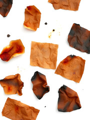 Naklejka premium A group of crumpled and burnt paper sheets in varying sizes with smudges and burn streaks on white background.