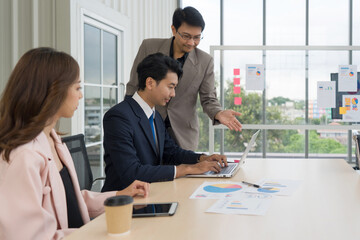 Business professional collaborating with enthusiasm while examining data on a laptop in a contemporary office setting.