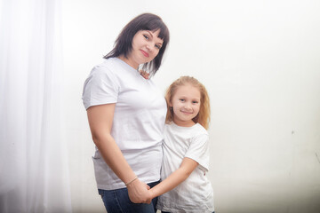 Mother and daughter smiling together in matching white shirts in a bright indoor setting