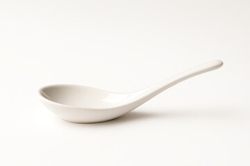 A sleek white ceramic spoon resting on a clean background. Ideal for showcasing culinary creativity, this spoon is perfect for serving soups, sauces, and other delicious dishes.