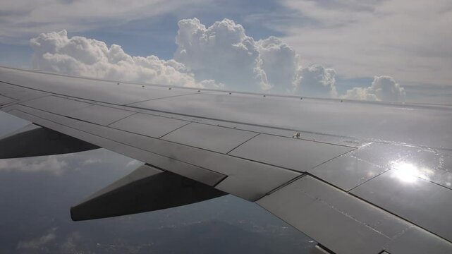 Commercial flight view over the wing with puffy clouds behind