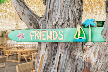 Wooden sign on tree with word FRIENDS. Creative concept of friendship spending time together...