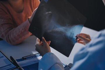 The doctor explain the old lady in retired life patient on lungs x-ray film and discuss treatment...